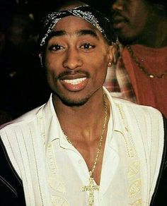 a man with a bandanna on his head and wearing a white shirt is smiling at the camera