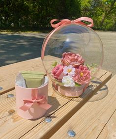 a pink box with flowers inside sitting on a wooden table