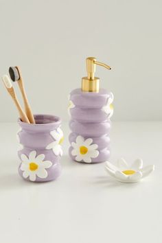 a bathroom set with soap dispenser, toothbrush holder and flower design