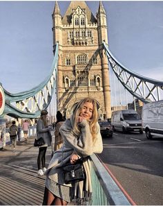 a woman standing on the side of a bridge talking on a cell phone