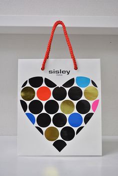 a paper bag with a heart made out of circles on the front and sides, hanging from a shelf