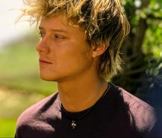 a close up of a person wearing a black shirt and a tree in the background