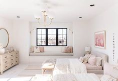 a bedroom with white walls and flooring has a large bed, two windows, and a couch