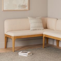 a white couch sitting on top of a wooden floor next to a book and pillow