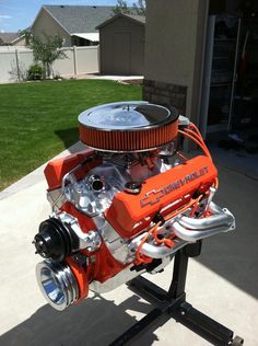 an orange and black engine sitting on top of a stand in front of a house