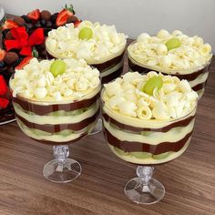 four desserts sitting on top of a wooden table next to some fruit and flowers