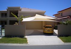 a yellow car is parked in front of a house with a large umbrella over it