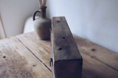 a wooden table with a vase on it and some sticks sticking out of the top