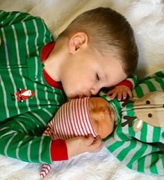 two young boys laying next to each other on a bed