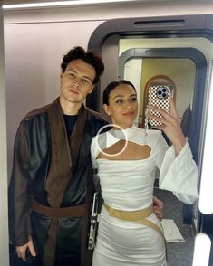 a man and woman taking a selfie in front of a star wars themed mirror