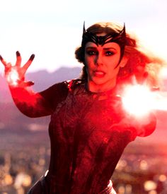 a woman dressed in black and red holding her hands out to the side while standing on top of a building