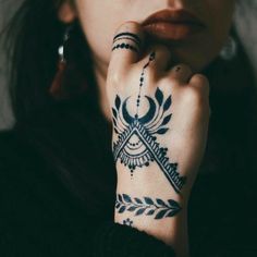 a close up of a person with tattoos on their arms and hands, holding her hand to her face