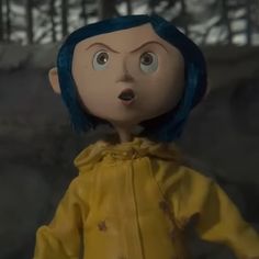 a doll with blue hair wearing a yellow raincoat and looking surprised at the camera