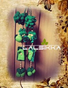 a bunch of green items hanging from a hook on a wooden wall with leaves around it