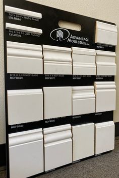 an assortment of white tile samples on display in a storefront window, with the words advantage moulder above them