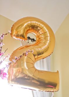 the number two balloon is in front of a vase with flowers