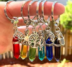 a person is holding four different colored glass keychains in their left hand and the other one has a tree on it