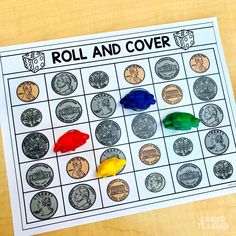 a roll and cover game with coins on the table next to it is colored crayons