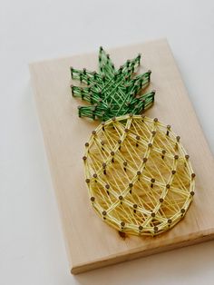 a string art pineapple sitting on top of a wooden board