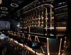 a dimly lit bar with stools and bottles on the shelves in front of it