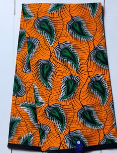 an orange and green patterned cloth hanging on a wall