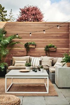 an outdoor living area with couches, tables and potted plants