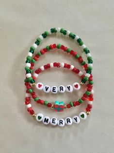 three beaded bracelets with the words merry written in white and green letters on them