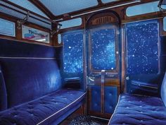 the inside of a train car with two blue couches in front of it and stars on the ceiling