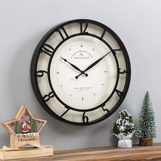 a black and white clock sitting on top of a wooden shelf next to a christmas tree