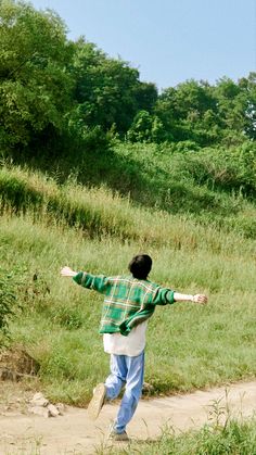 a man walking down a dirt road with his arms outstretched