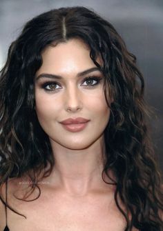 a close up of a person with long hair and brown eyeshadow wearing a black dress