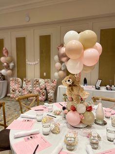 a teddy bear sitting on top of a table surrounded by balloons and confetti