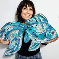 a woman holding up a fish made out of fabric