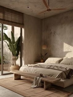 a bedroom with a large bed sitting next to a sliding glass door and potted plant