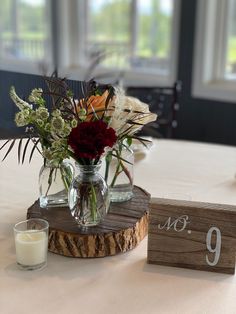 a vase filled with flowers sitting on top of a table next to a wooden block