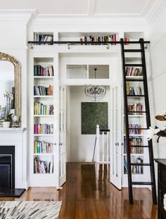 a living room filled with furniture and a ladder leading up to a book shelf full of books