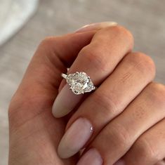 a woman's hand holding a ring with two diamonds on it and the middle finger