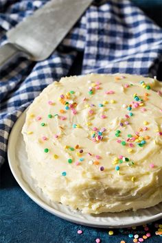 a cake with white frosting and sprinkles on a plate