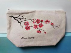 a white purse with red flowers painted on the front and bottom, sitting on a blue surface