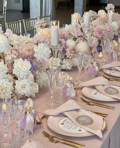 the table is set with pink and white flowers, candles, and napkins on it