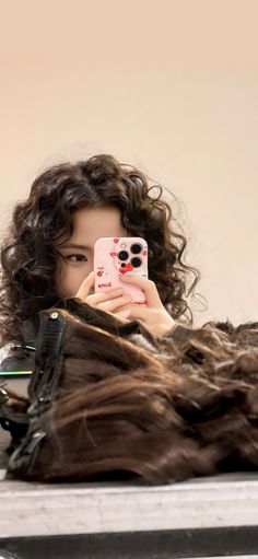 a woman is taking a selfie with her hair in front of her face and holding a cell phone