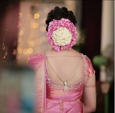 a woman wearing a pink and white sari with flowers in her hair