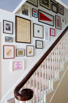 there is a staircase with many framed pictures on the wall next to it and a banister