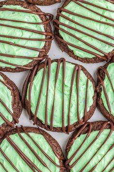 cookies with green frosting and chocolate drizzled on top are arranged in rows