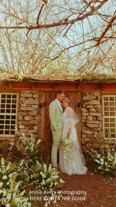 a bride and groom standing in front of a stone building