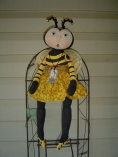 the doll is wearing a yellow dress and black shoes, sitting on a metal stand