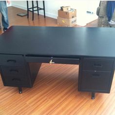 a black desk sitting on top of a hard wood floor