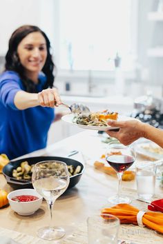 two people sitting at a table with plates of food and wine glasses in front of them