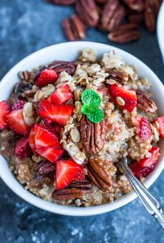 a bowl filled with oatmeal topped with strawberries and pecans