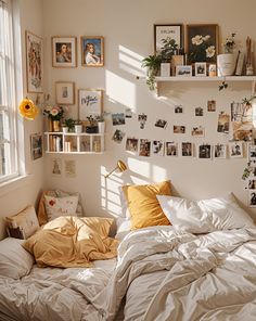 an unmade bed in a bedroom with pictures on the wall and shelves above it